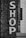 Large white block letters spelling 'SHOP' are painted vertically on a textured brick wall. The wall is a mix of old grey bricks and white tile, creating a vintage urban look.