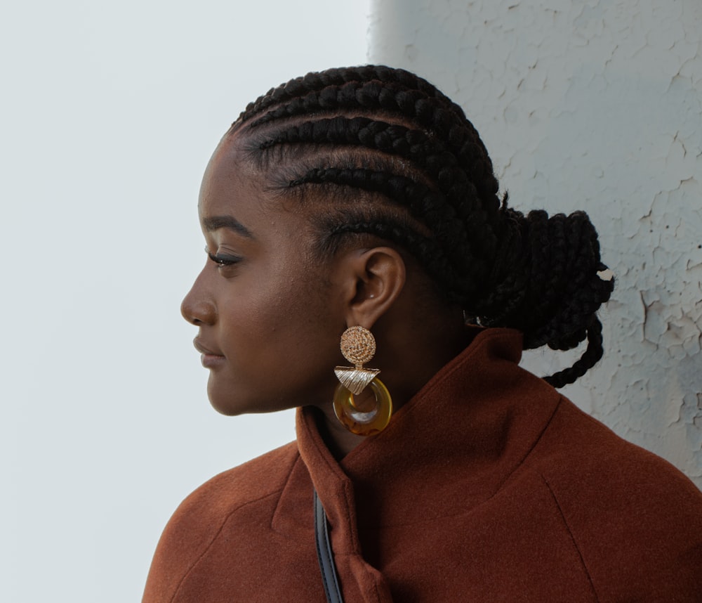 woman in brown coat wearing gold earrings