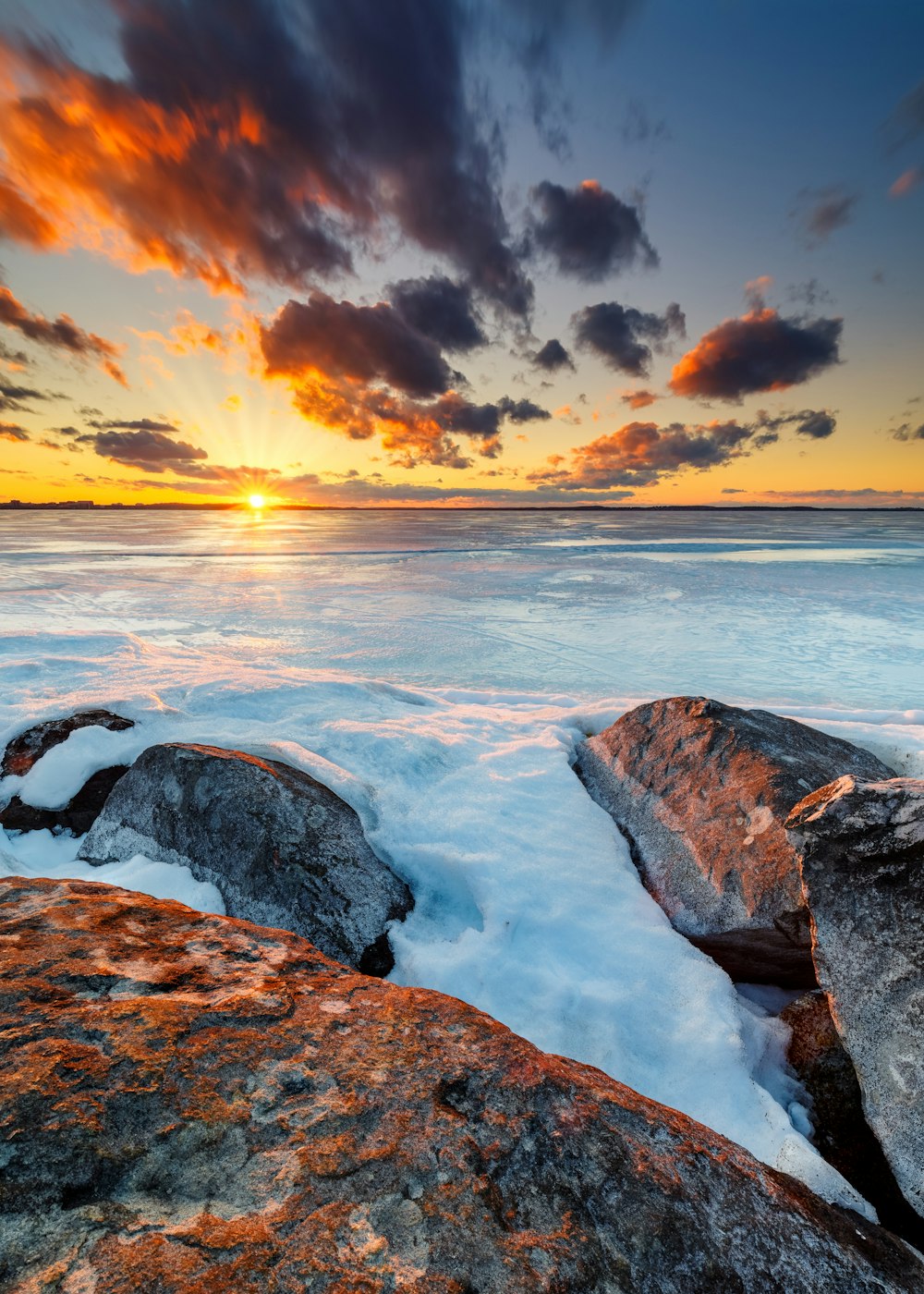 rocky shore under cloudy sky during sunset