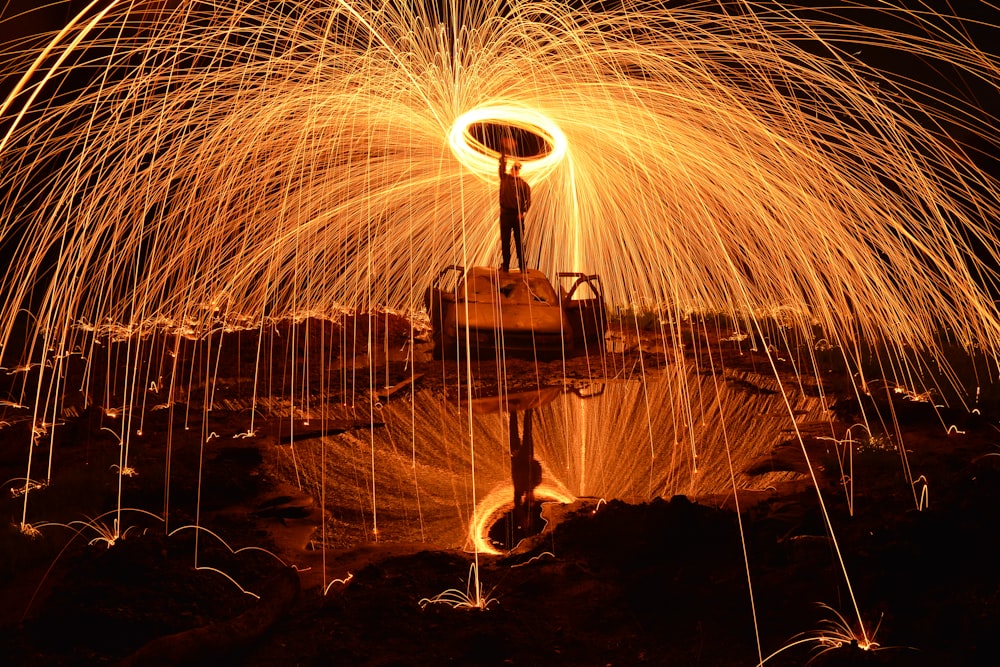 man standing on wooden dock with fire works display