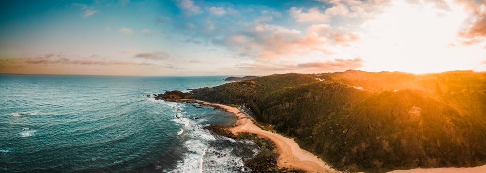 an aerial view of a beach and ocean at sunset