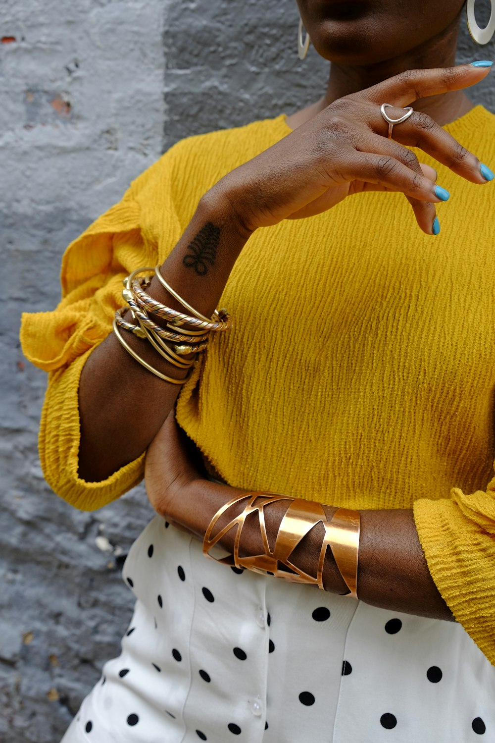 mujer en suéter amarillo con pulsera de oro