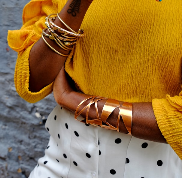 woman in yellow sweater wearing gold bracelet