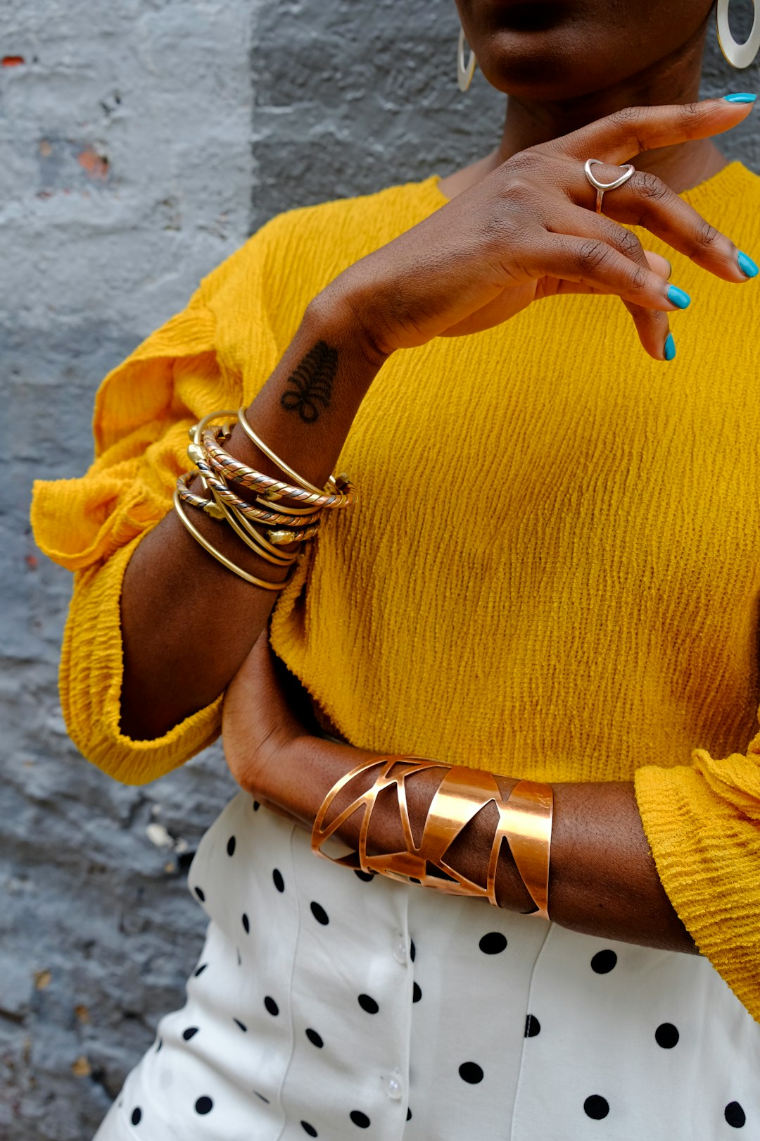 woman in yellow sweater wearing gold bracelet