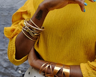 woman in yellow sweater wearing gold bracelet