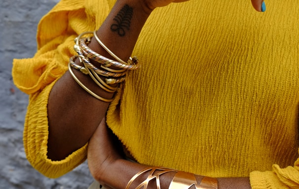 woman in yellow sweater wearing gold bracelet