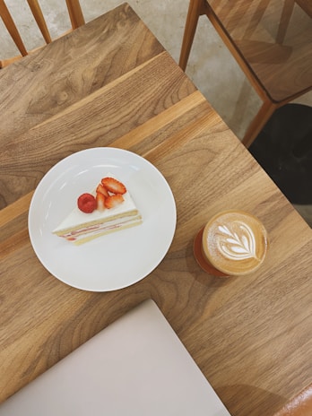 Close-up of a beautifully crafted latte and a slice of homemade cake on a rustic ceramic plate.