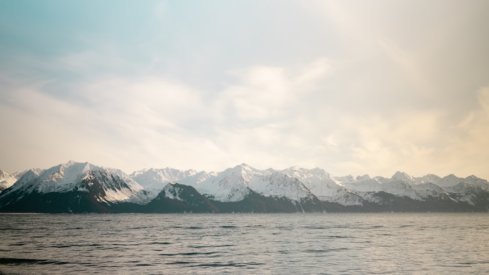 snow covered mountain near body of water during daytime