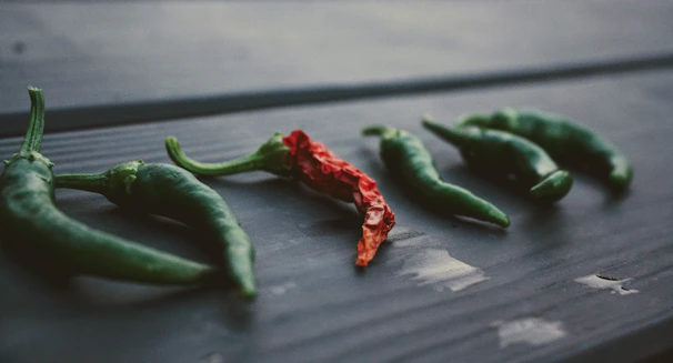 Close-up of fresh serrano and poblano chiles laid out on rustic wooden table.