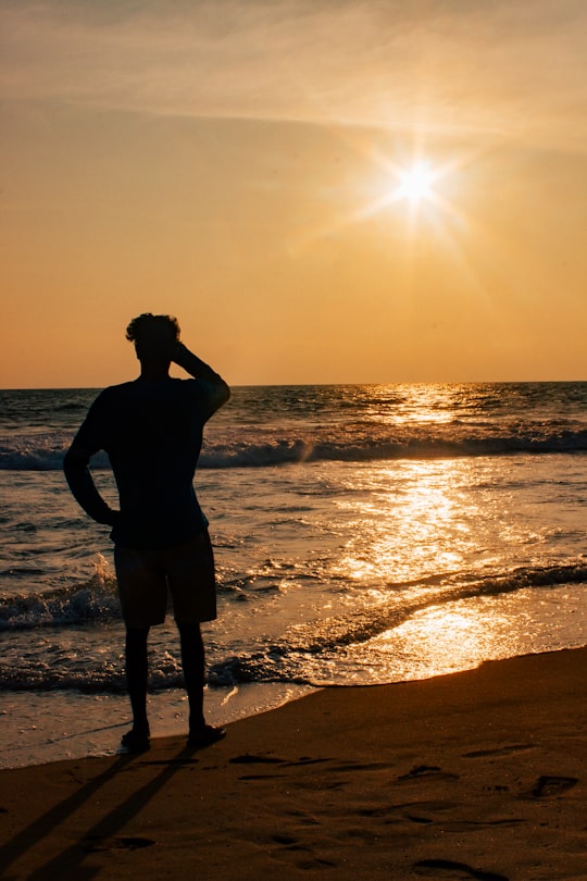 silhouette of woman standing on beach during sunset in Kovalam India