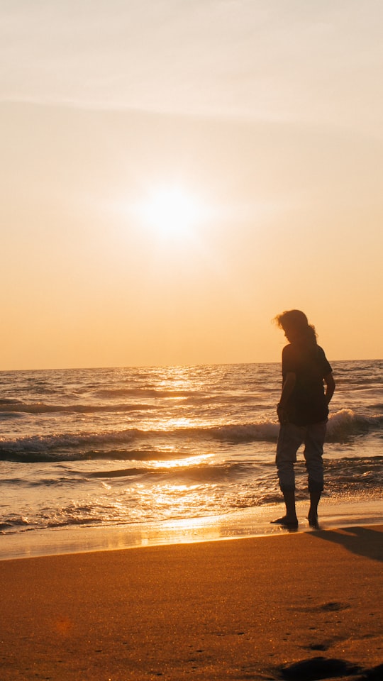 silhouette of man standing on beach during sunset in Kovalam India