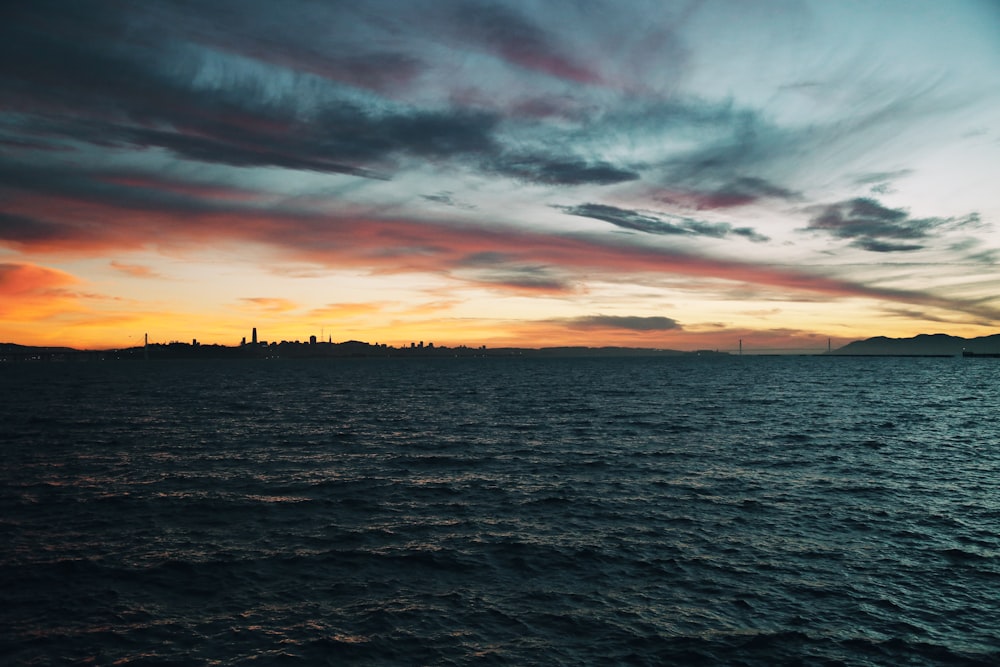 body of water under cloudy sky during sunset