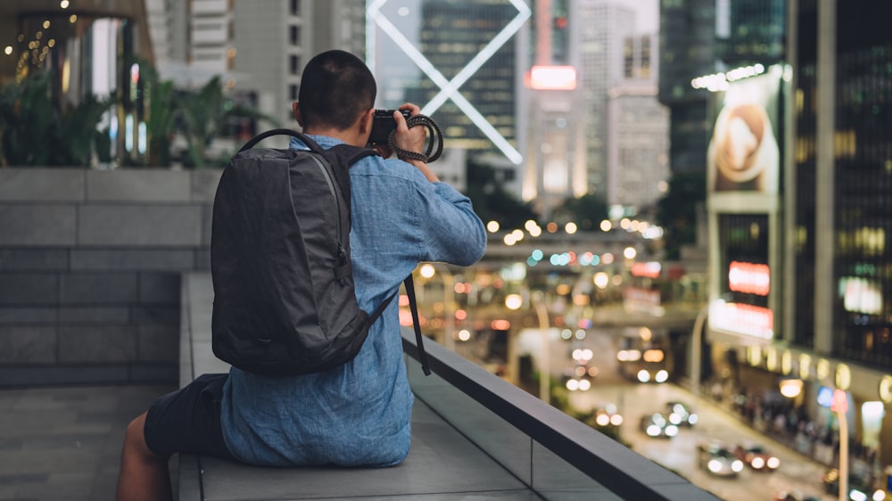 man in blue denim jeans and black backpack holding black dslr camera