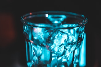 Close-up of a glass filled with luminous juice and ice cubes sparkling under soft light