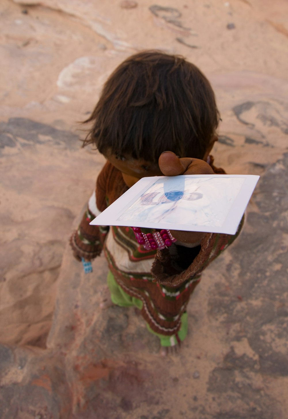 boy in brown shirt holding white printer paper