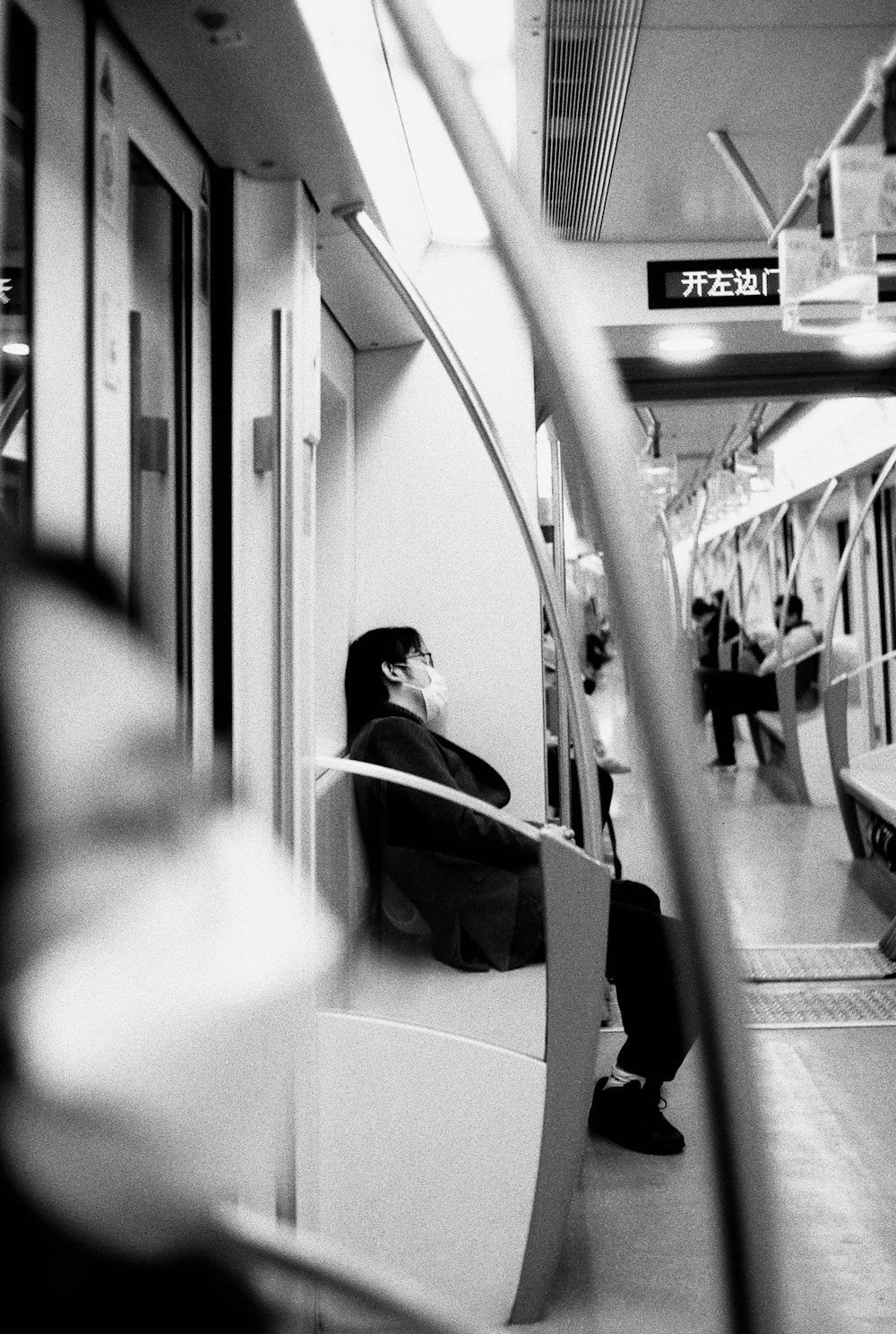 기차에 앉아 검은 재킷을 입은 여자의 회색조 사진