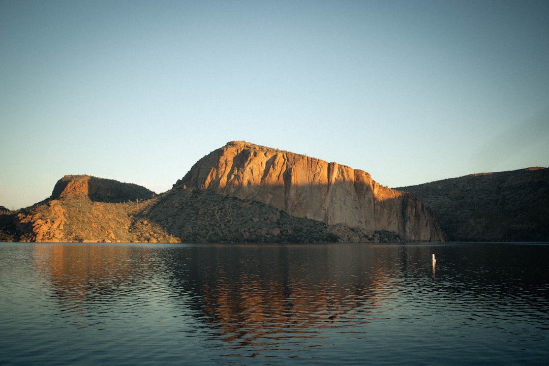 brown mountain beside body of water during daytime