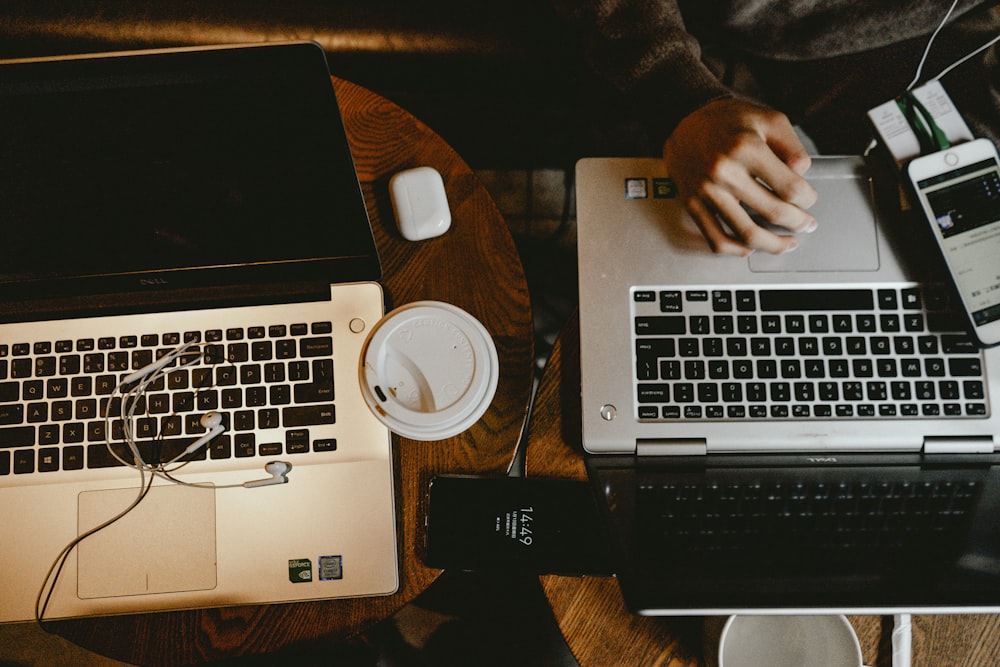 person using macbook pro on brown wooden table