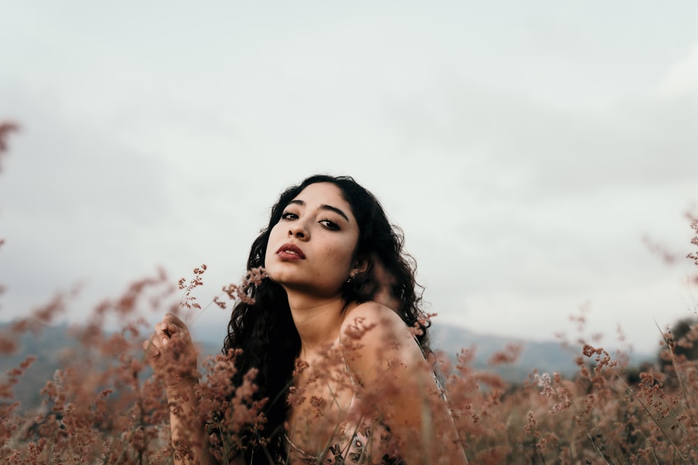 woman in brown floral dress standing on brown grass field during daytime