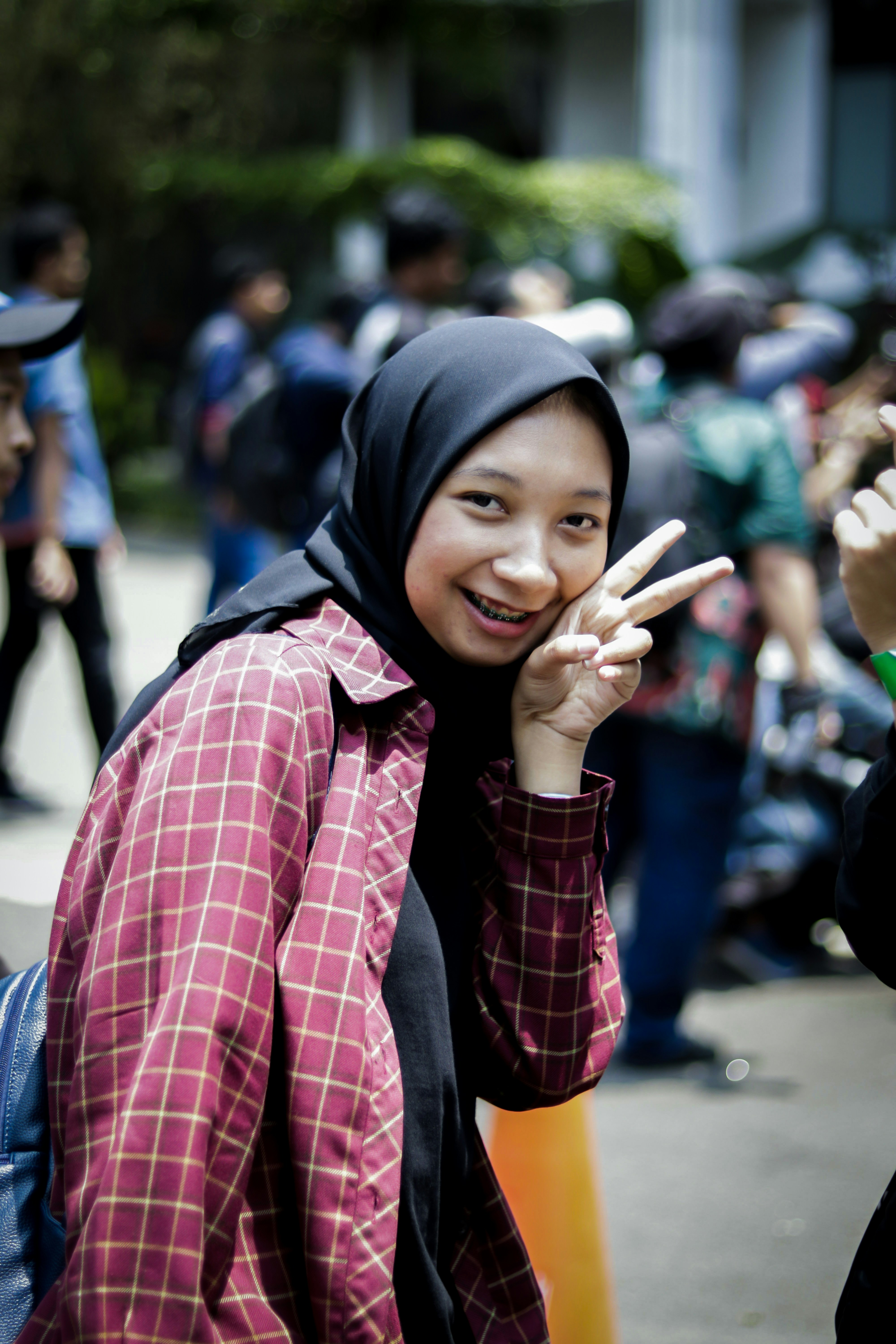Wanita dengan kemeja kotak-kotak merah dan hitam mengenakan hijab hitam