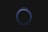 A circular pattern, resembling a vortex or swirling effect, is depicted against a dark background. The circle is composed of thin, semi-transparent lines with varying shades of blue.