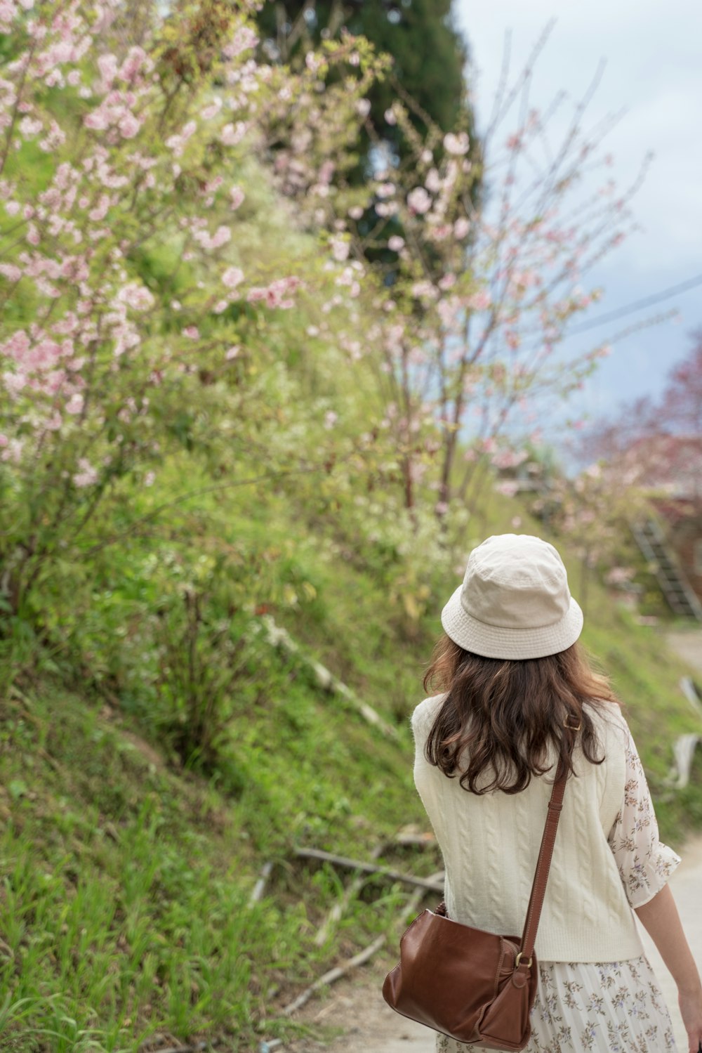 femme en bonnet en tricot blanc debout près des arbres verts pendant la journée