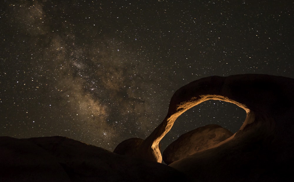 brown rock formation under starry night