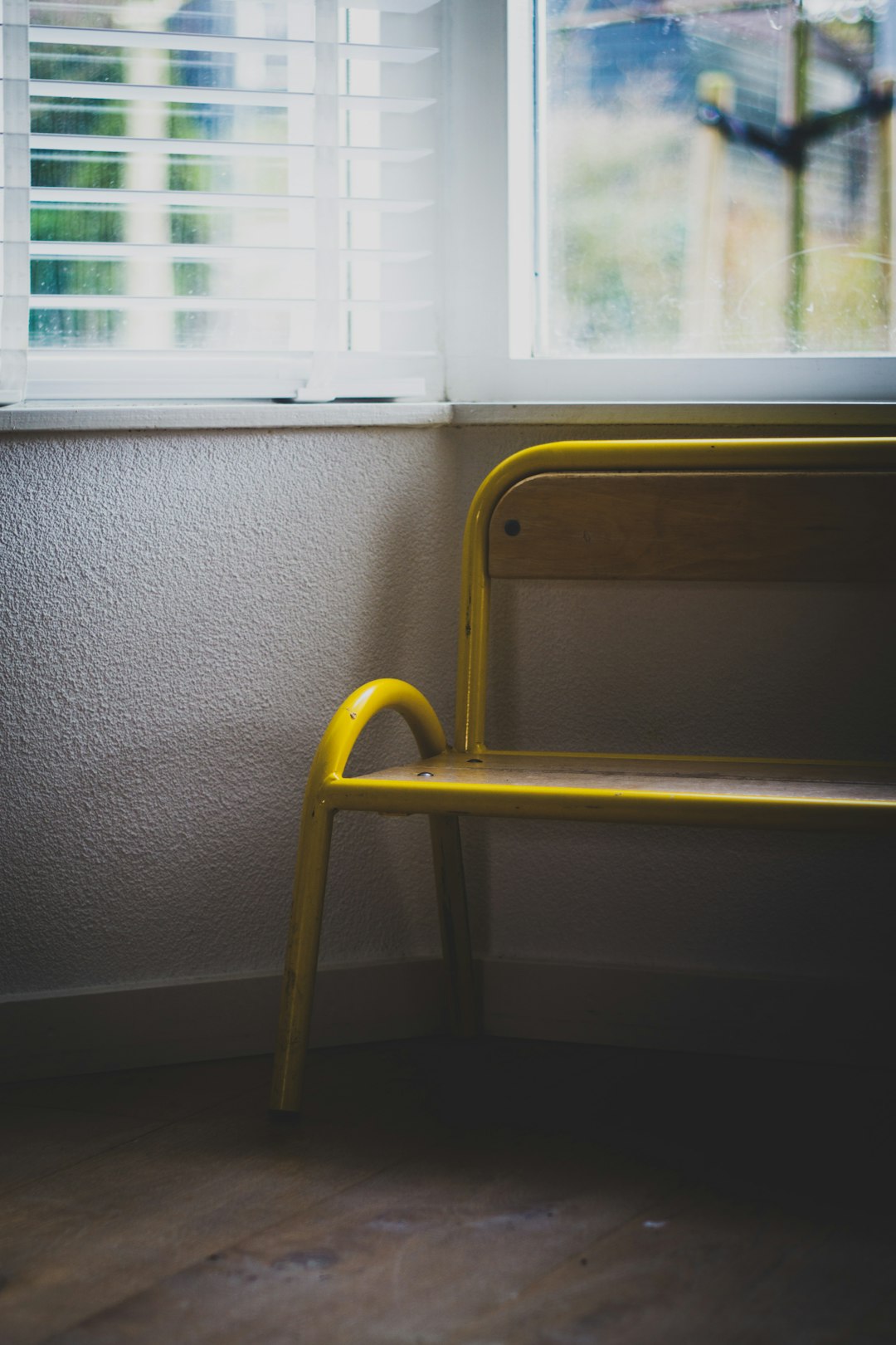 yellow chair beside white window blinds