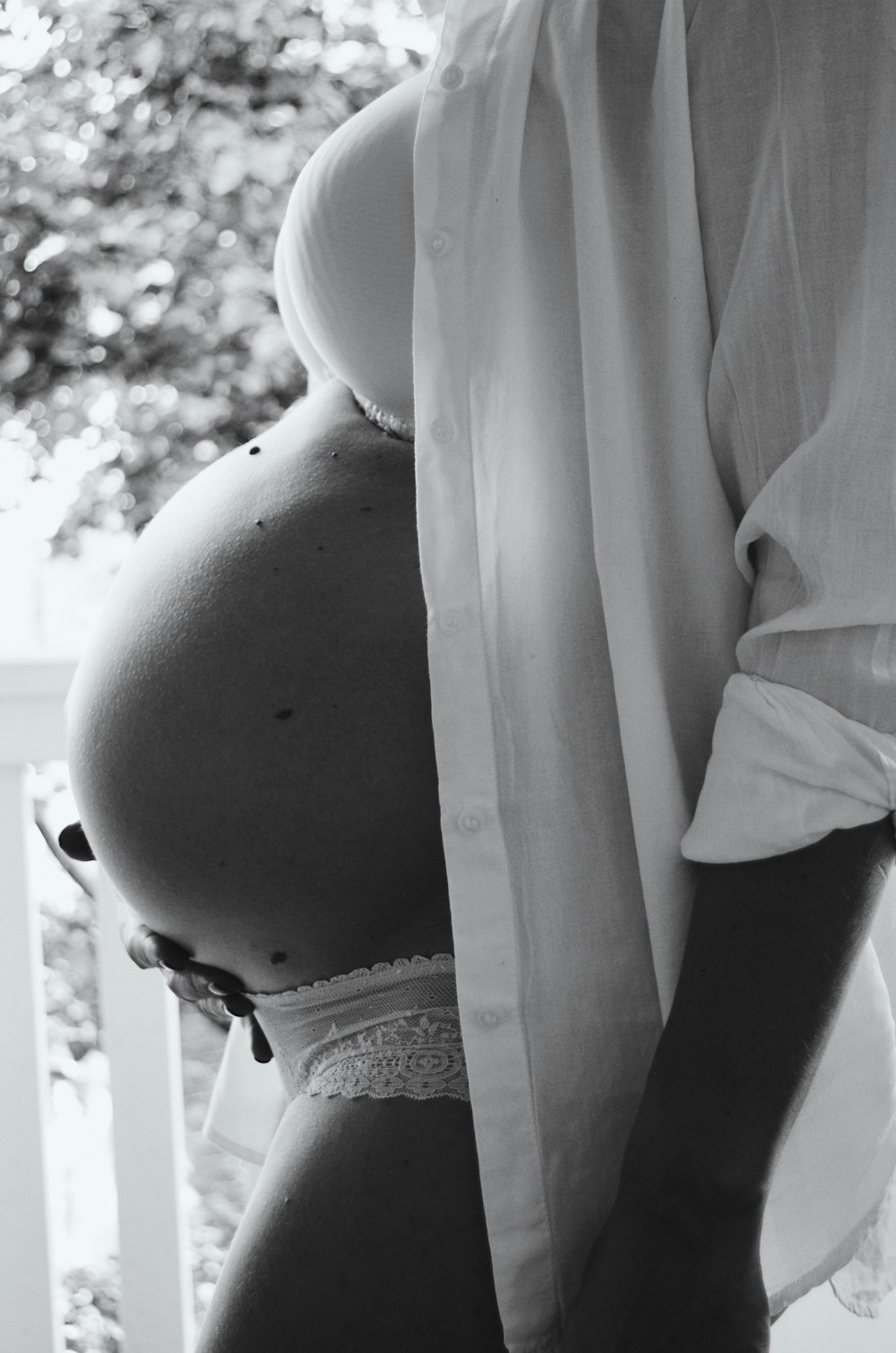 grayscale photo of pregnant woman wearing white brassiere
