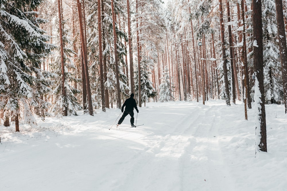 person in black jacket walking on snow covered ground during daytime