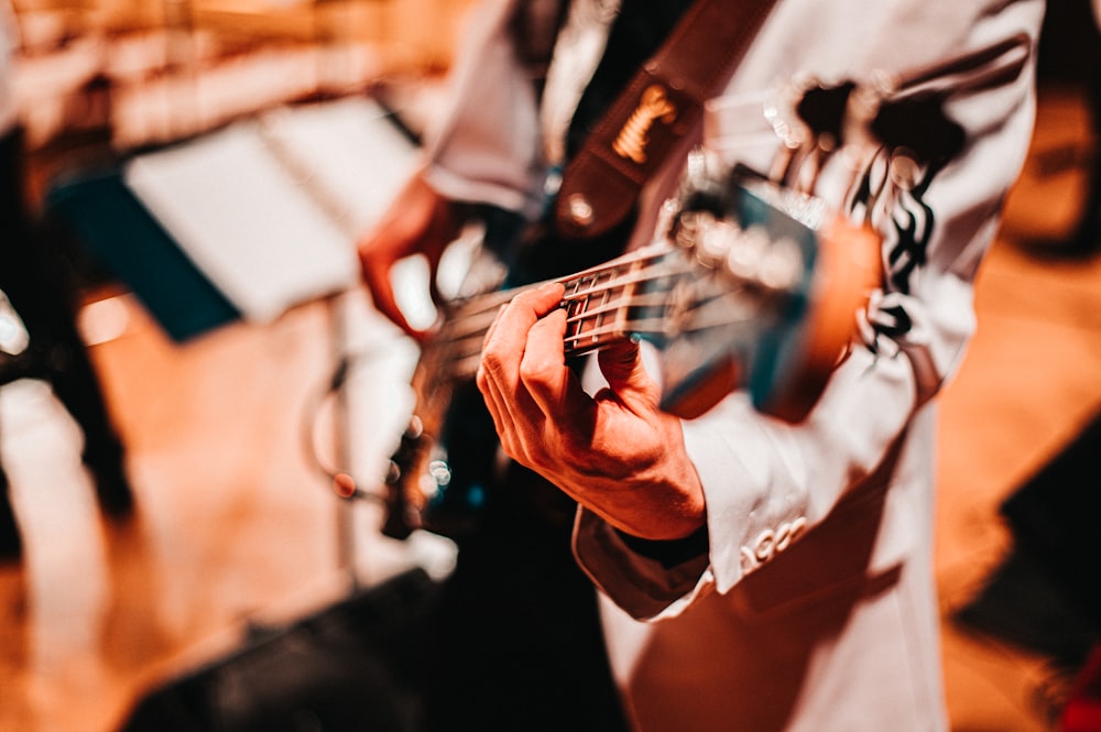 man in white dress shirt playing electric guitar