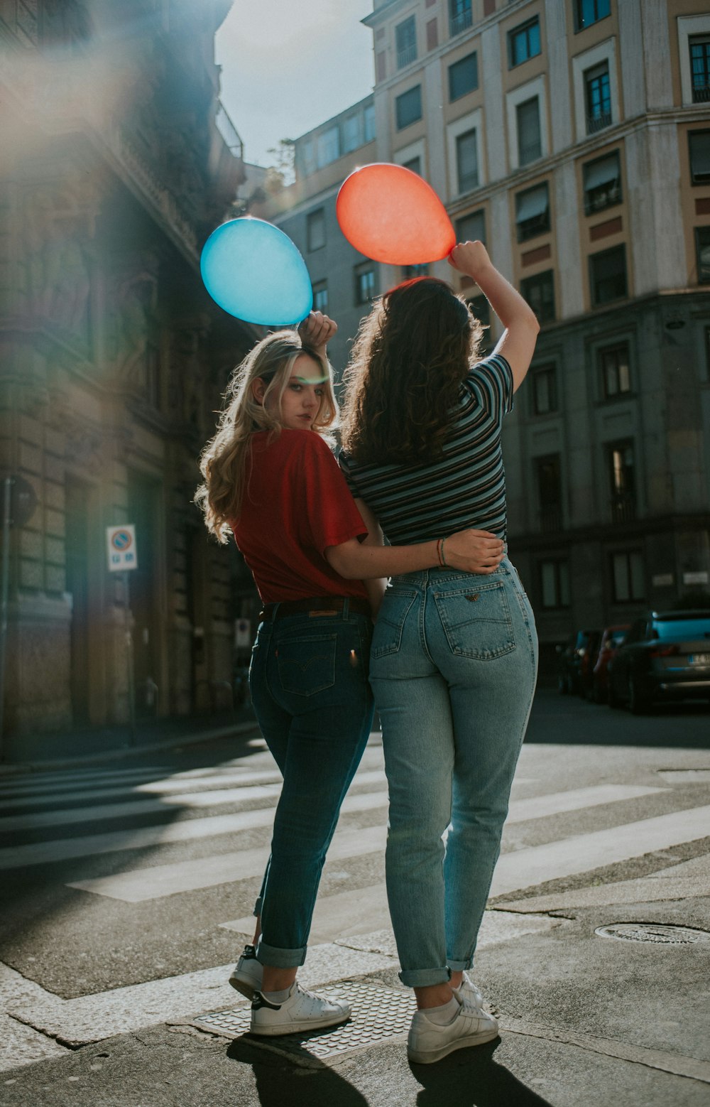 woman in red long sleeve shirt and blue denim jeans holding balloons