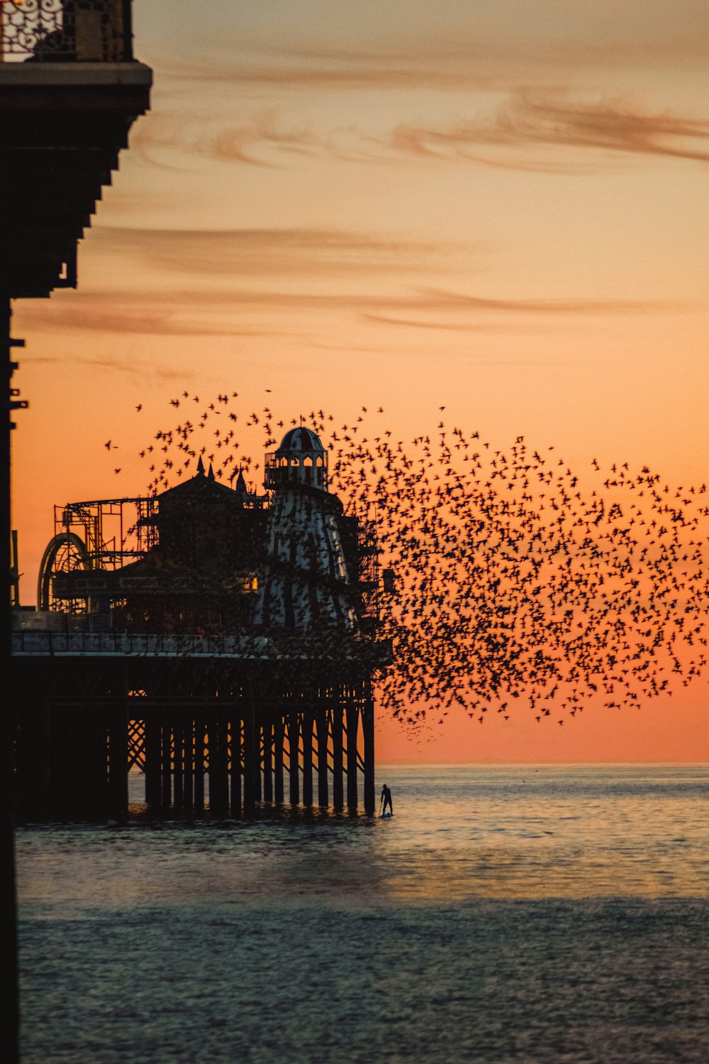 Silhouette eines Mannes, der während des Sonnenuntergangs auf dem Dock steht