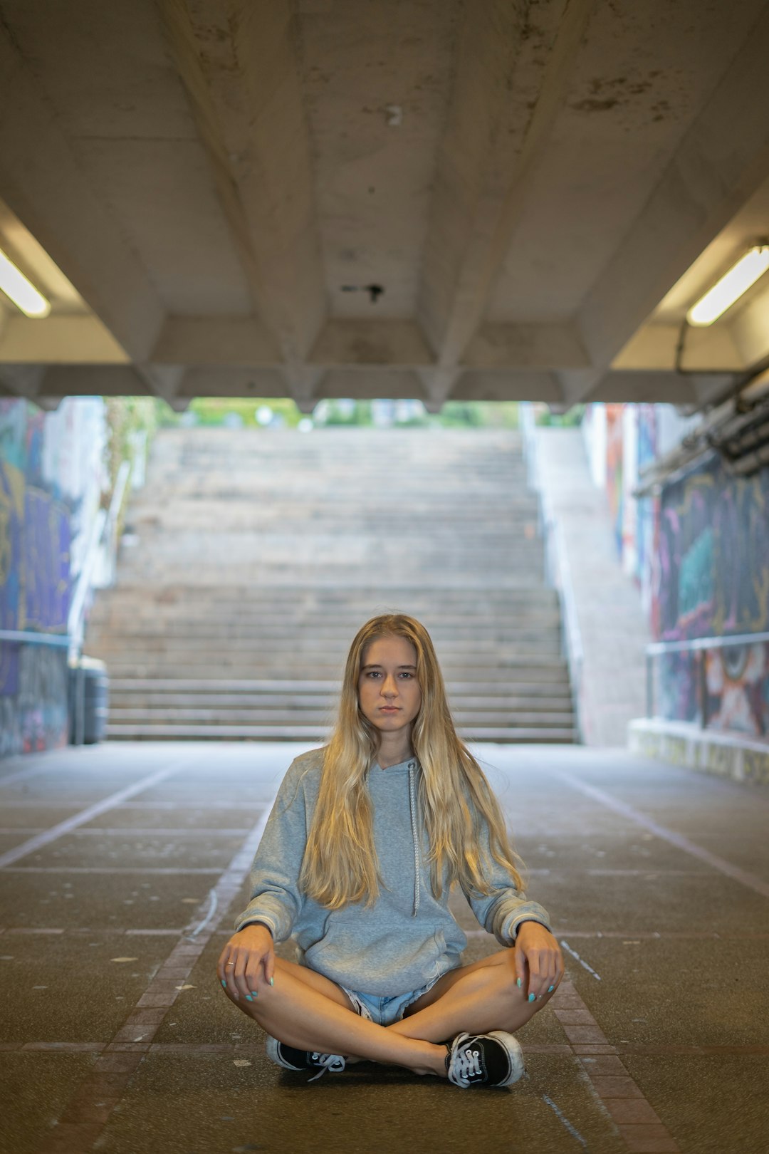 woman in gray long sleeve shirt sitting on sidewalk during daytime