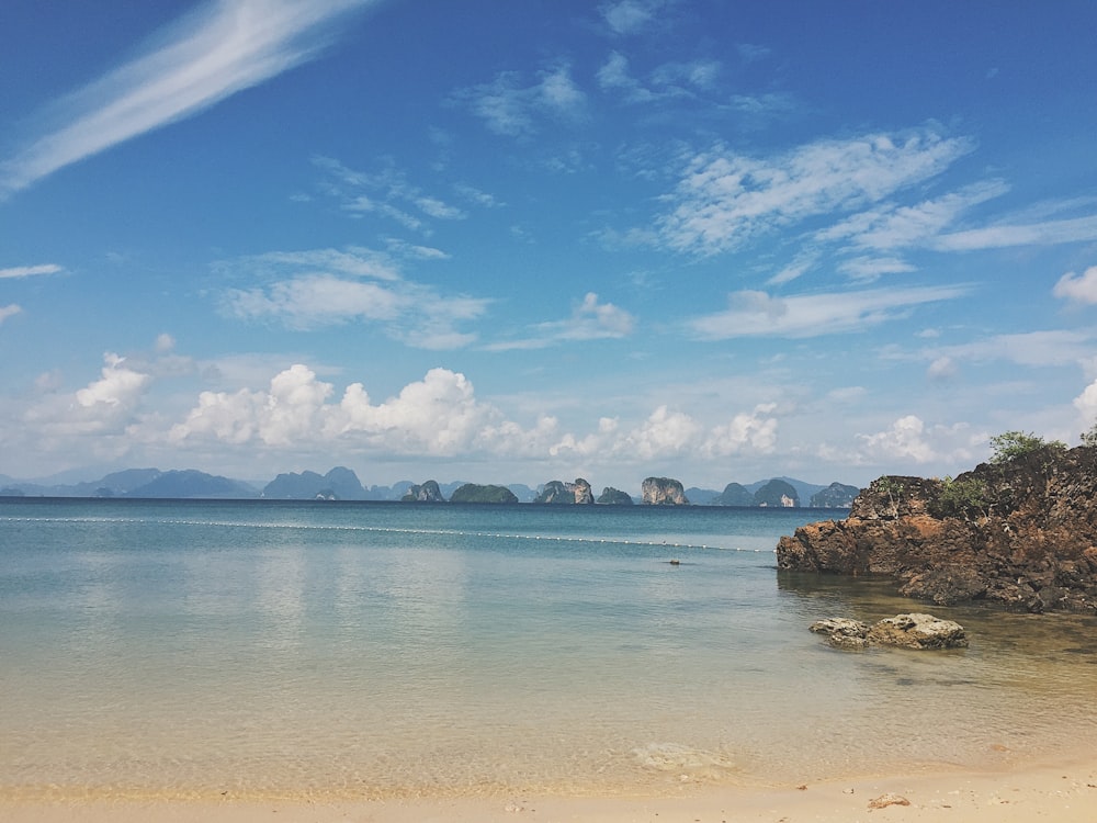 brown rock formation on sea under blue sky during daytime