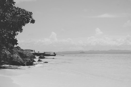 grayscale photo of boat on sea shore in Krabi Thailand