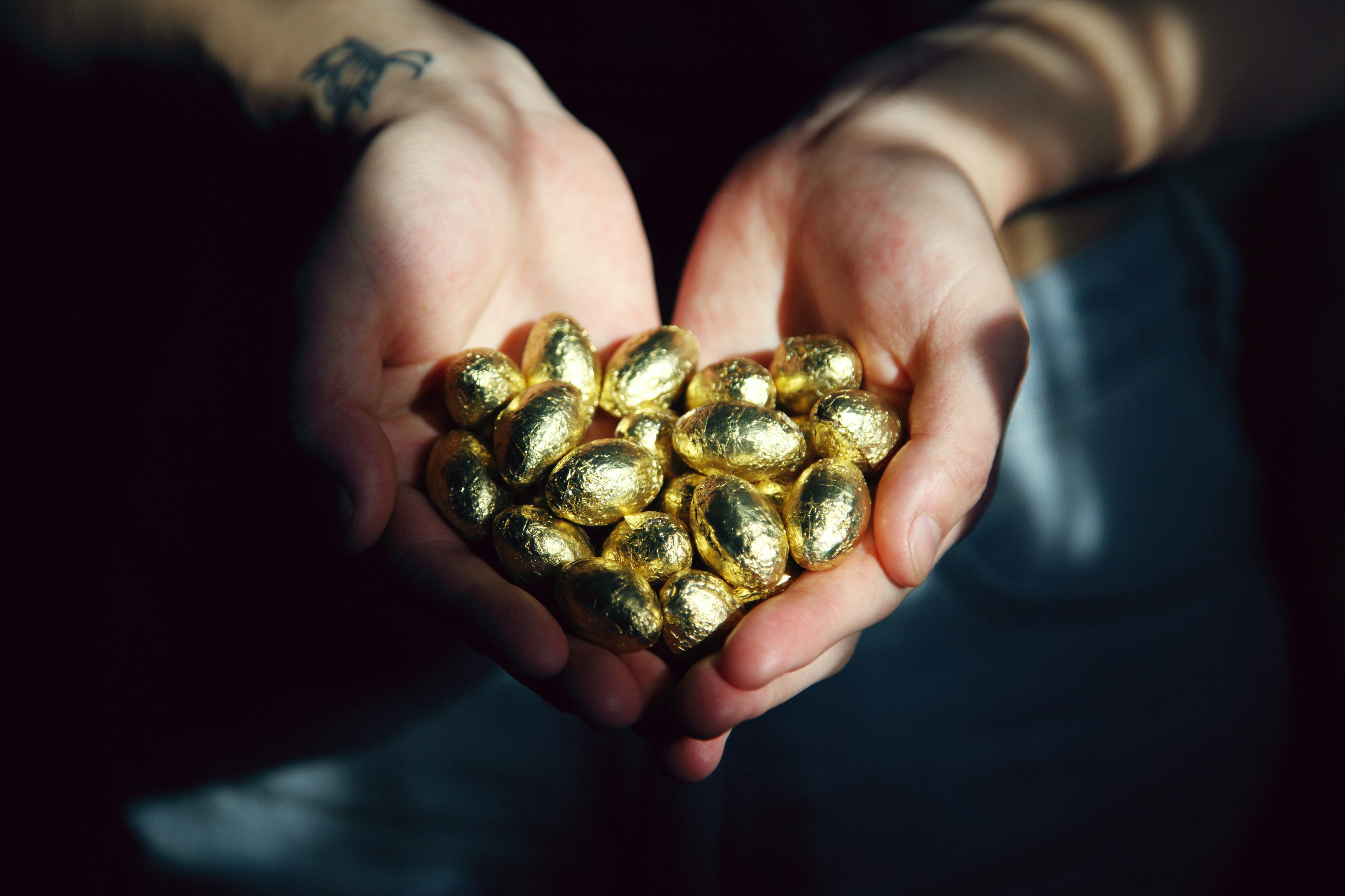 Person holding golden foil wrapped chocolate candy eggs.