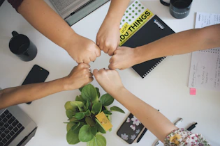 five fists bumping over office desk