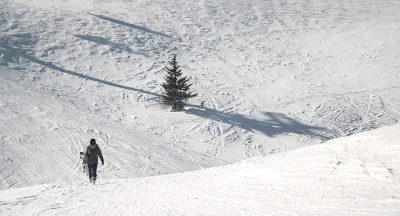 person in black jacket and black pants on snow covered mountain during daytime
