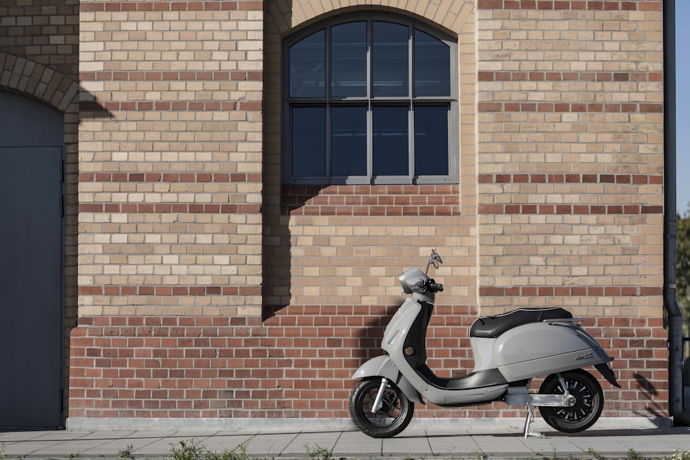 black and red motor scooter parked beside brown brick wall