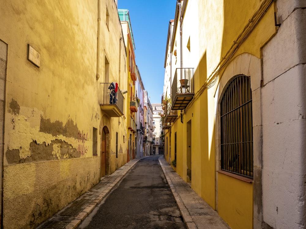 empty street between yellow concrete buildings during daytime