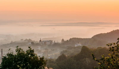 A serene village landscape at dawn with children walking to school under a saffron sky.