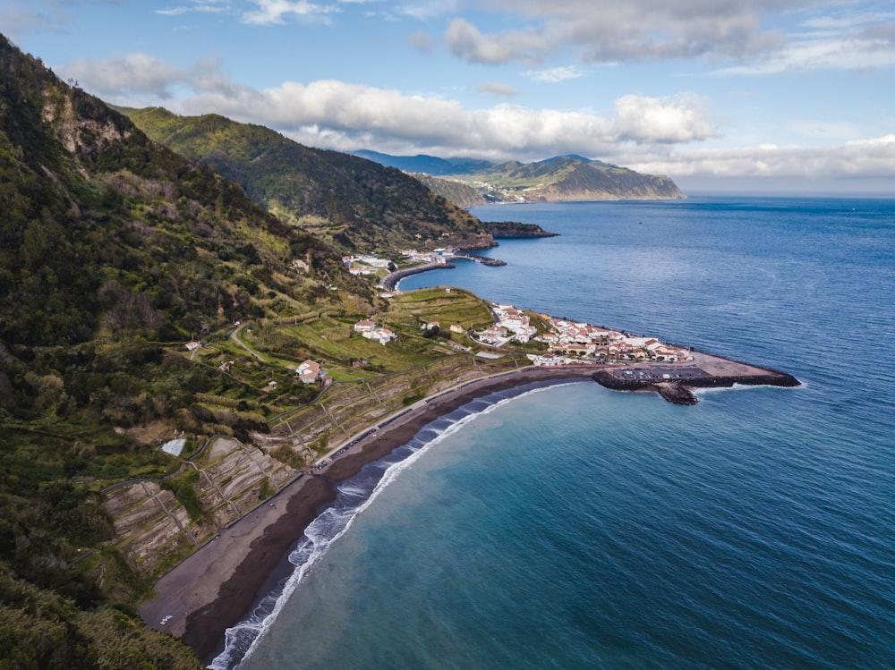 green mountain beside blue sea under blue sky during daytime