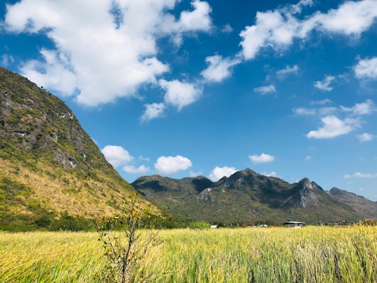 green grass field near mountain under blue sky during daytime in Hua Hin Thailand