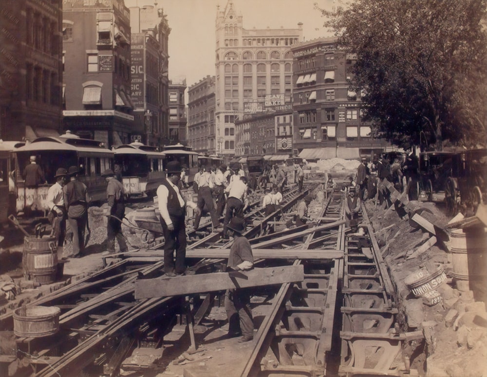 Foto en escala de grises de trabajadores de pie en el sitio de construcción