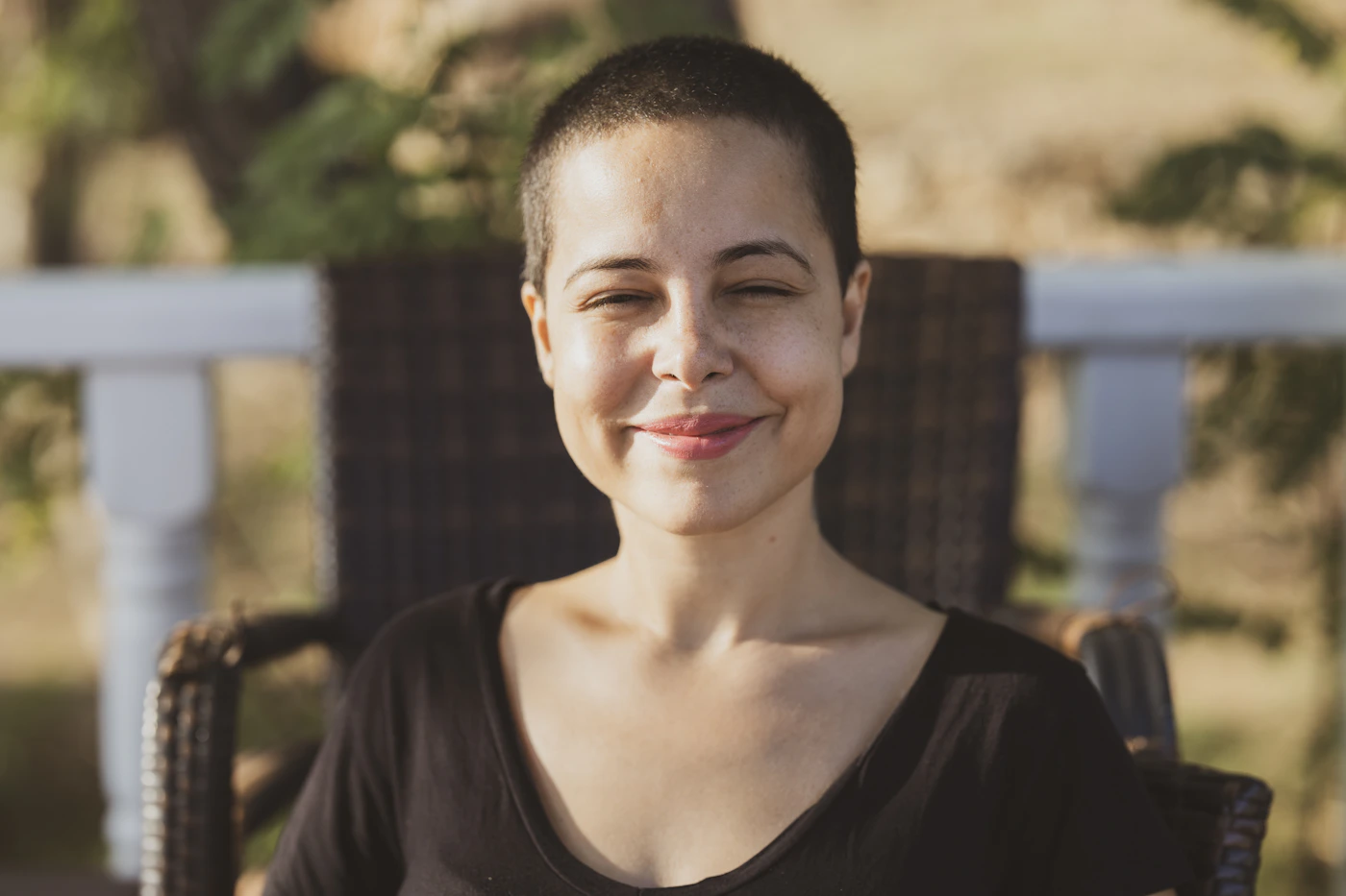 Femme aux cheveux très courts souriant dans une lumière naturelle