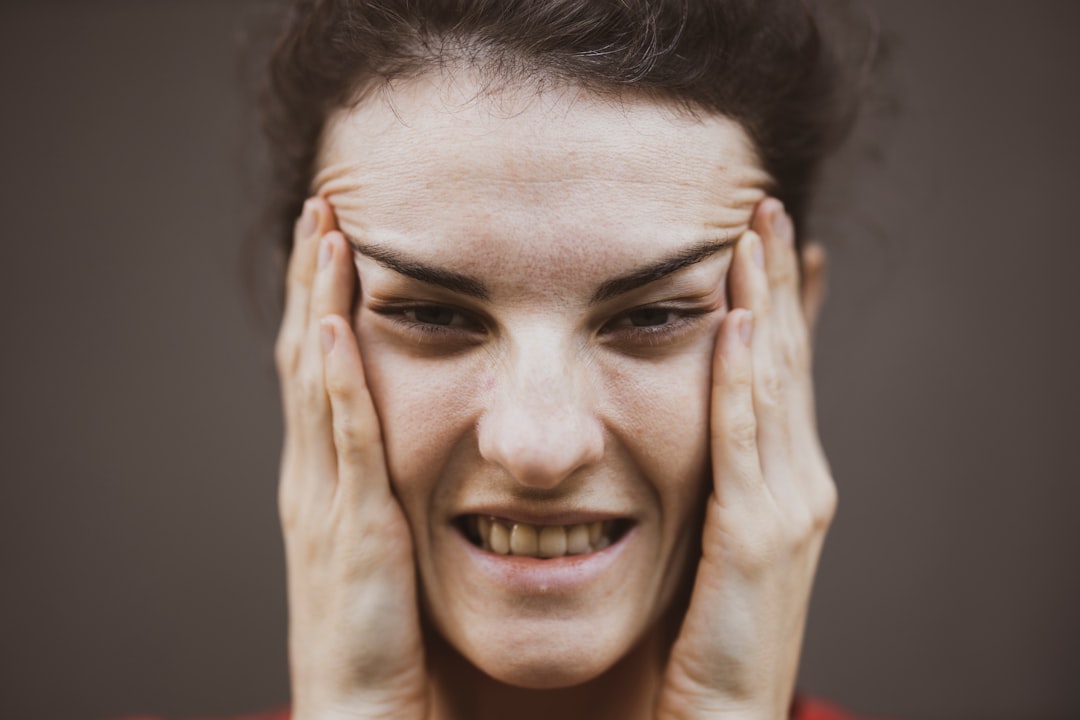 woman in red shirt holding her face