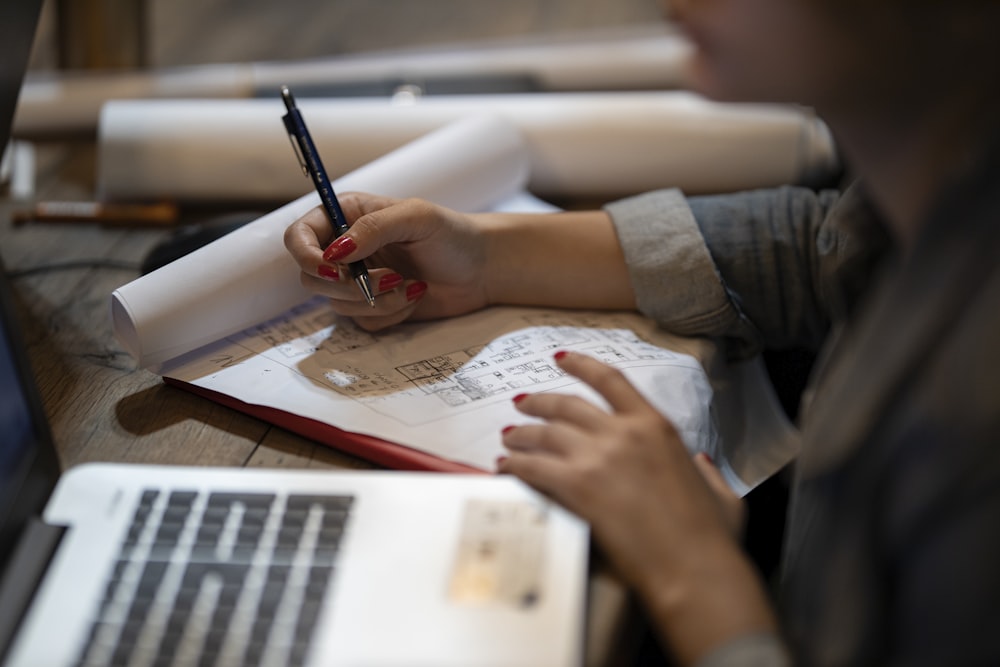 person in white shirt writing on white paper