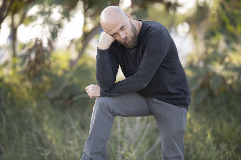 man in black long sleeve shirt and gray pants sitting on green grass during daytime