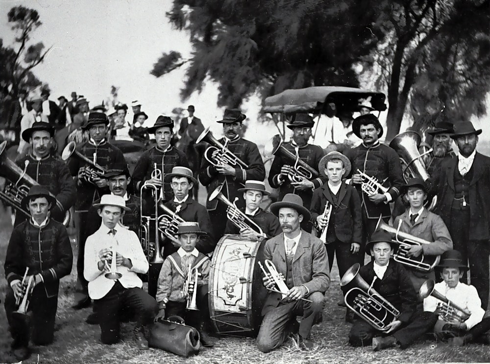 grayscale photo of men in black hat playing musical instrument